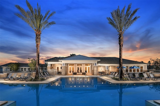 pool at dusk featuring a patio area