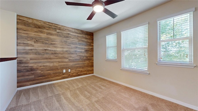 carpeted spare room with ceiling fan and wooden walls