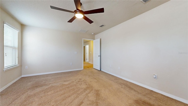 spare room with ceiling fan, plenty of natural light, and light carpet