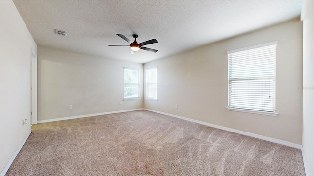 spare room featuring ceiling fan, light colored carpet, and a textured ceiling