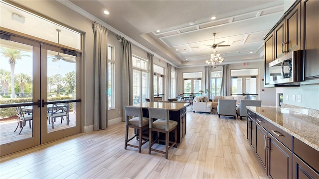 dining room featuring a raised ceiling, french doors, an inviting chandelier, and light hardwood / wood-style flooring