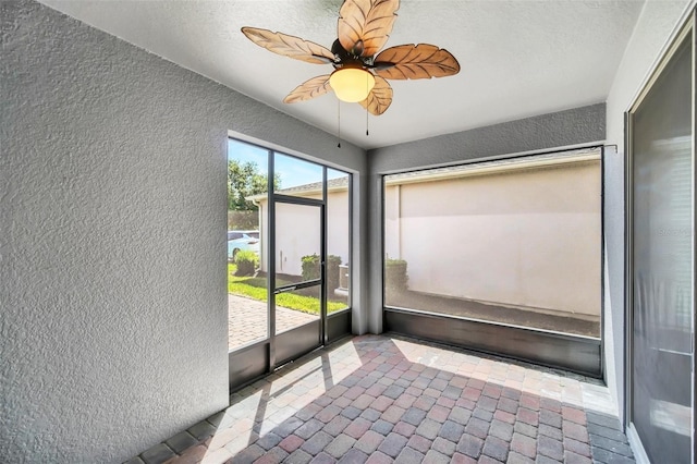 unfurnished sunroom featuring ceiling fan and a wealth of natural light