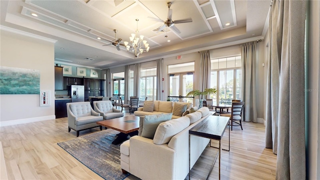 living room with light hardwood / wood-style floors, a raised ceiling, and ceiling fan with notable chandelier