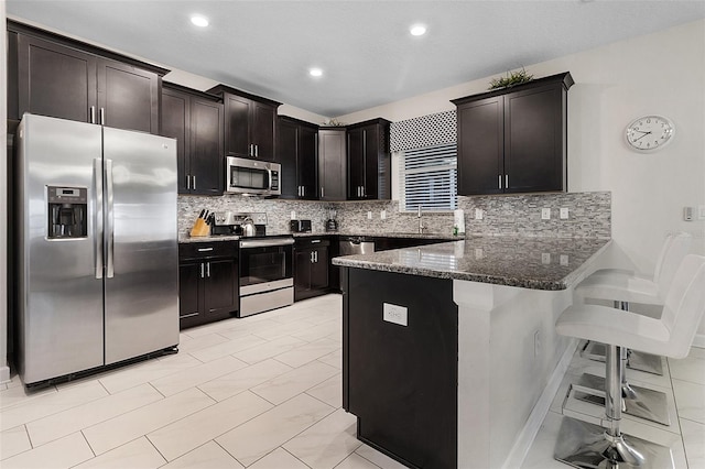 kitchen featuring a kitchen bar, light tile floors, tasteful backsplash, and appliances with stainless steel finishes