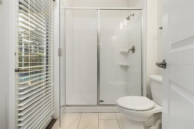 bathroom featuring a shower with door, tile flooring, and toilet