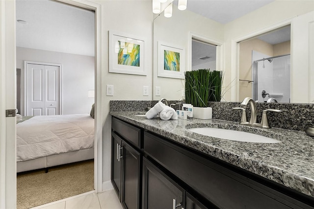 bathroom featuring a shower with shower door, dual vanity, and tile floors