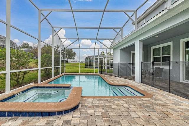 view of pool with an in ground hot tub, glass enclosure, and a patio area