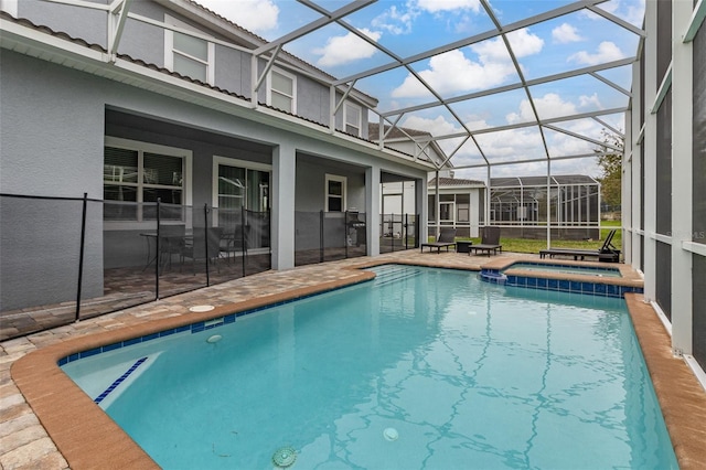 view of pool with a patio area, glass enclosure, and an in ground hot tub