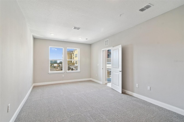 carpeted empty room featuring a textured ceiling