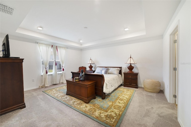 bedroom featuring a raised ceiling and light colored carpet