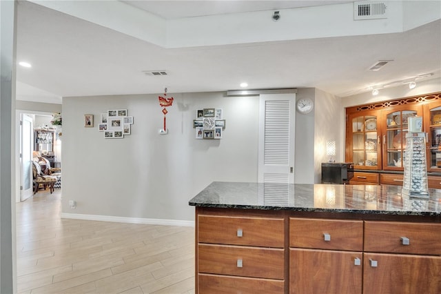 kitchen featuring light hardwood / wood-style floors, rail lighting, and dark stone counters