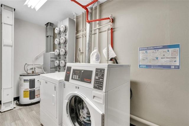 washroom featuring water heater, light hardwood / wood-style floors, and independent washer and dryer