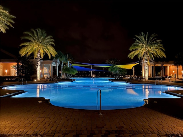 pool at twilight with a patio and a community pool