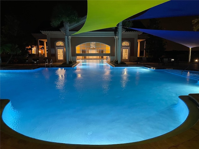 pool at twilight with a patio area and a community pool