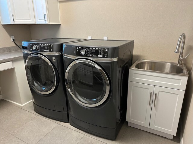 washroom featuring light tile patterned floors, independent washer and dryer, a sink, and cabinet space