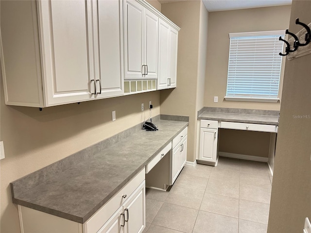 kitchen featuring light tile patterned floors, white cabinetry, and built in desk