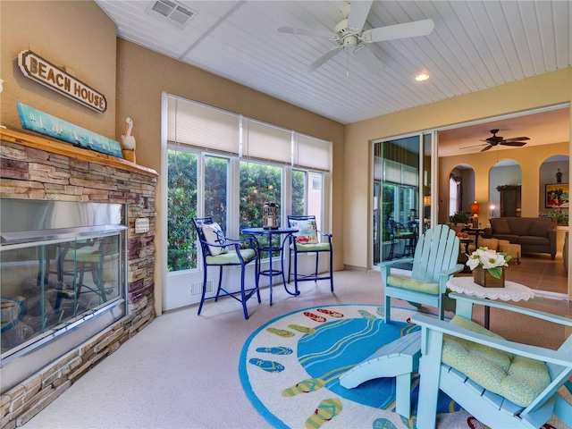 sunroom / solarium with a fireplace, visible vents, arched walkways, and a ceiling fan