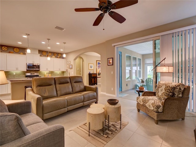 living room featuring arched walkways, light tile patterned floors, recessed lighting, visible vents, and baseboards