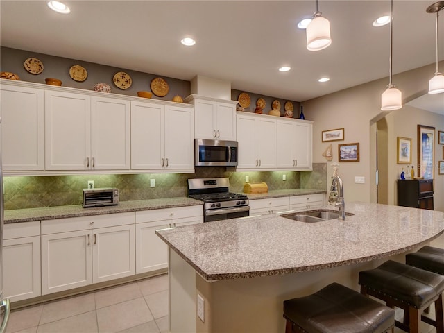 kitchen with light tile patterned floors, a sink, white cabinetry, appliances with stainless steel finishes, and tasteful backsplash