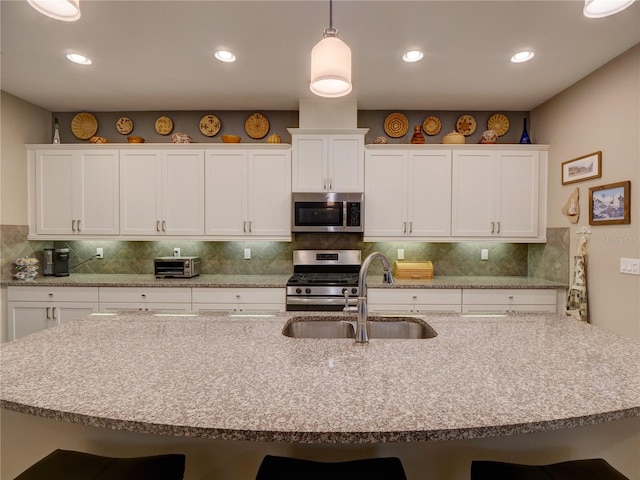 kitchen featuring backsplash, appliances with stainless steel finishes, a breakfast bar, and a sink