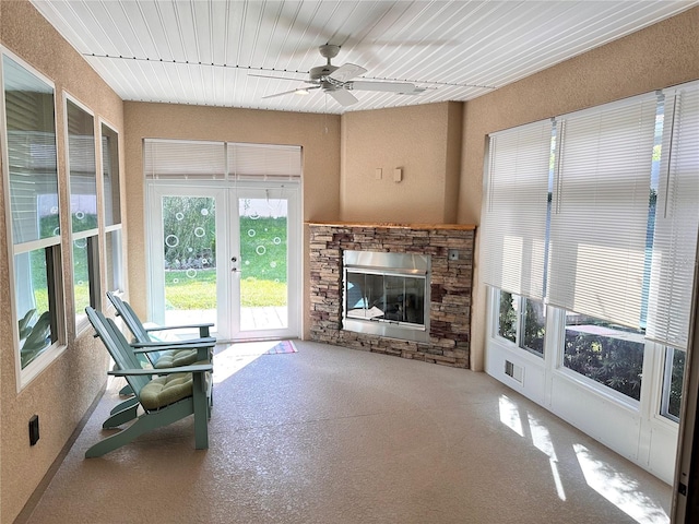 interior space with visible vents, carpet flooring, a ceiling fan, and a stone fireplace