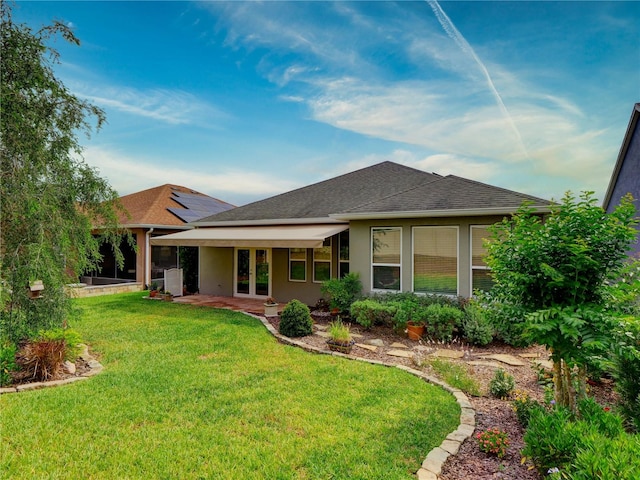 rear view of house featuring a shingled roof, french doors, a yard, and stucco siding