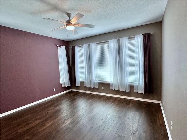 empty room with a ceiling fan, a healthy amount of sunlight, baseboards, and wood finished floors