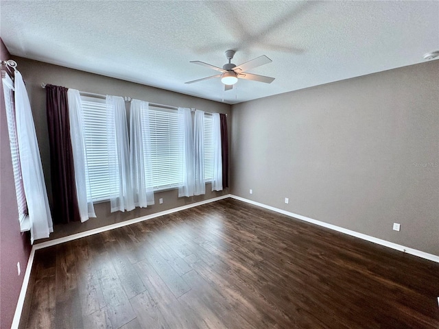 unfurnished room featuring a textured ceiling, dark wood-style flooring, a ceiling fan, and baseboards