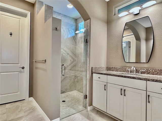 full bathroom with marble finish floor, baseboards, a shower stall, and vanity