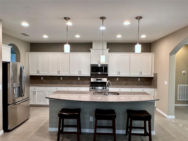 kitchen with visible vents, decorative backsplash, arched walkways, stainless steel appliances, and a sink