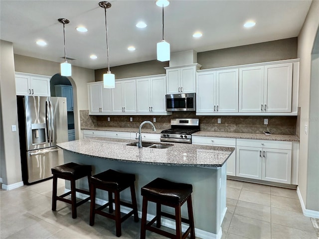 kitchen with arched walkways, stainless steel appliances, backsplash, and a sink