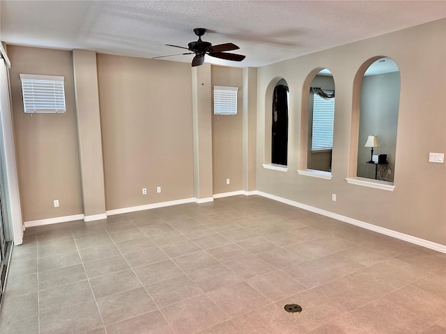 tiled spare room featuring a ceiling fan, baseboards, and a textured ceiling