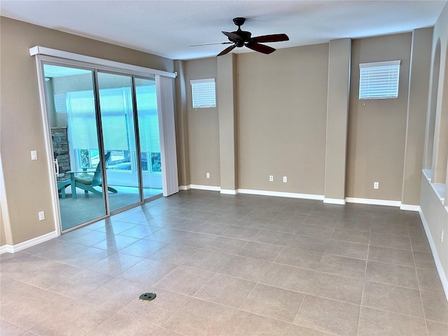 tiled spare room featuring ceiling fan and baseboards