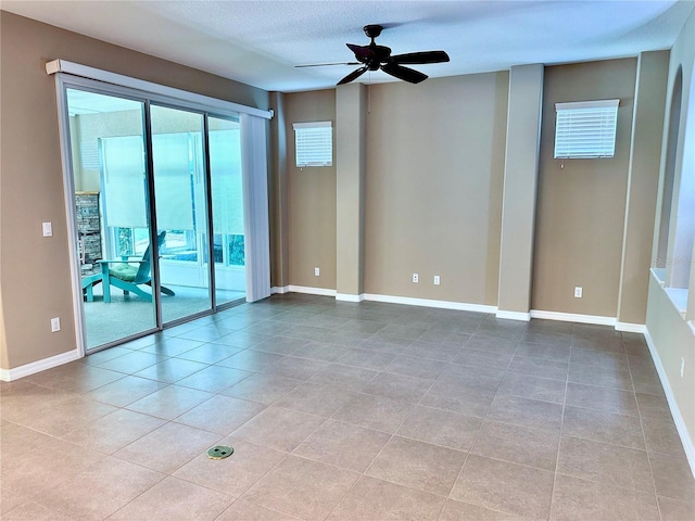 tiled spare room featuring a ceiling fan, a textured ceiling, and baseboards