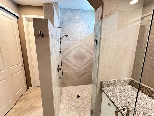 bathroom with a textured wall and a shower stall