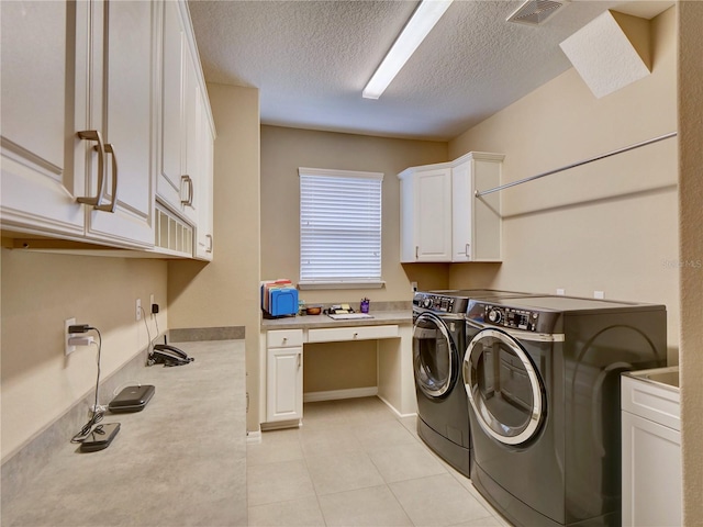 laundry room with a textured ceiling, light tile patterned flooring, visible vents, washer and dryer, and cabinet space