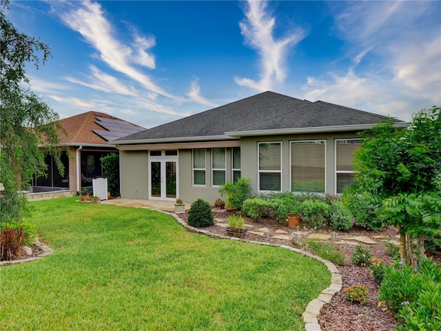 back of house featuring a shingled roof, french doors, a yard, and stucco siding