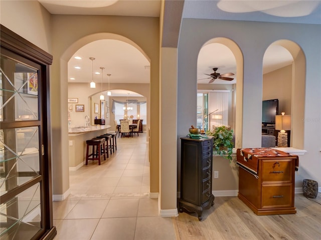 hallway with arched walkways, light tile patterned flooring, baseboards, and recessed lighting