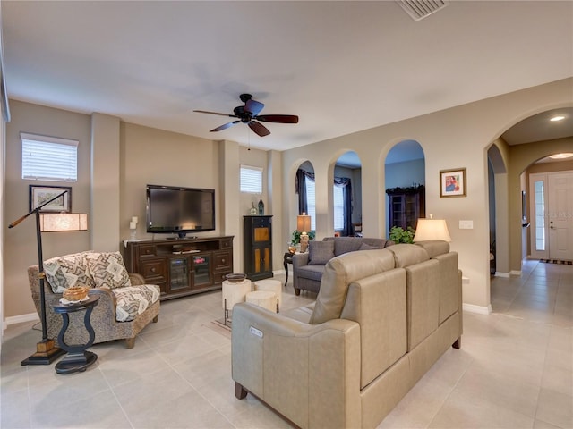 living area featuring visible vents, arched walkways, baseboards, ceiling fan, and light tile patterned flooring