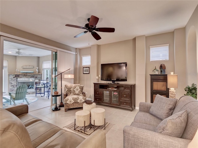 living room featuring light tile patterned floors, ceiling fan, and a fireplace