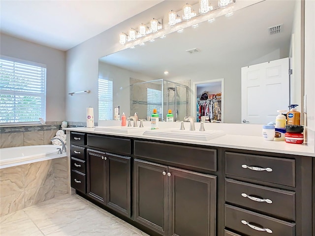 bathroom with vanity with extensive cabinet space, double sink, shower with separate bathtub, and tile floors