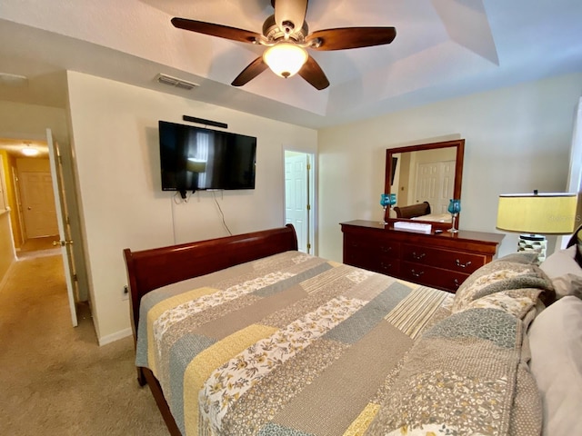 bedroom featuring a raised ceiling, ceiling fan, and carpet flooring