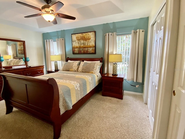 bedroom with carpet floors, ceiling fan, and a tray ceiling