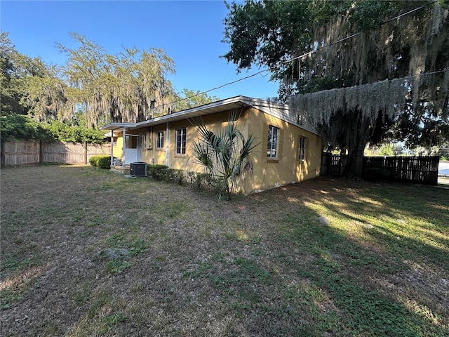 view of side of home featuring a yard and central AC