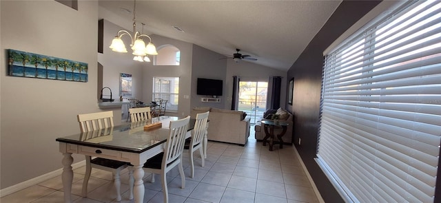 tiled dining space featuring vaulted ceiling, ceiling fan with notable chandelier, and a textured ceiling