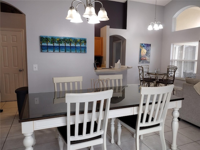 dining room with a notable chandelier, a towering ceiling, and light tile patterned flooring