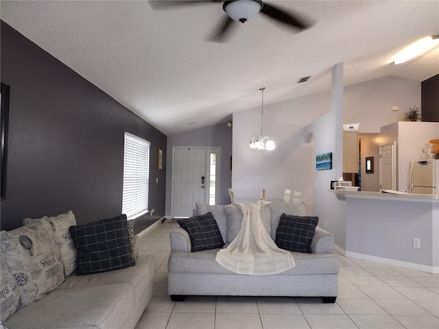 tiled living room featuring ceiling fan with notable chandelier, vaulted ceiling, and a textured ceiling