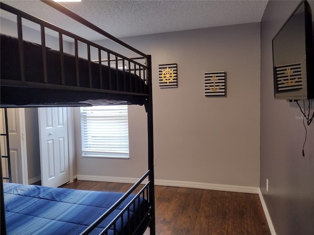 bedroom featuring a textured ceiling and dark hardwood / wood-style flooring