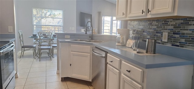 kitchen with sink, white cabinets, backsplash, light tile patterned floors, and stainless steel appliances