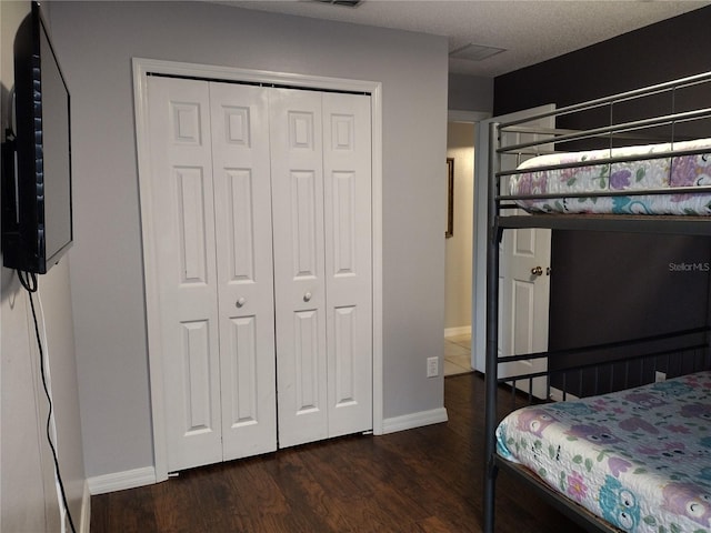 bedroom with dark hardwood / wood-style flooring and a closet